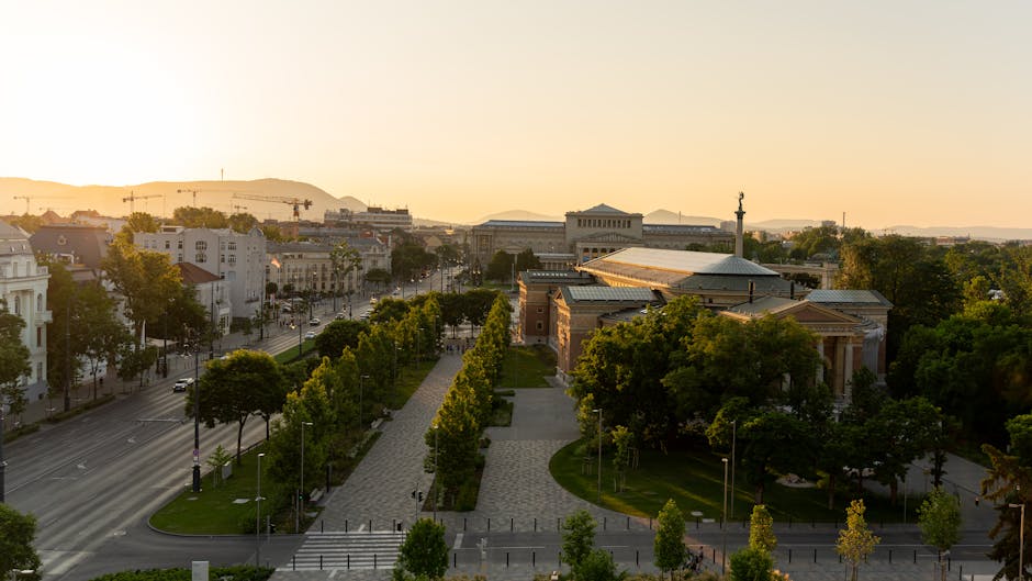 Stunning aerial view of Budapest cityscape at sunset, showcasing iconic architecture and urban greenery.