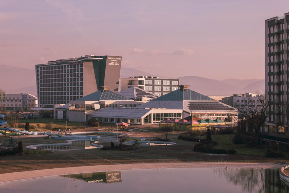 A modern hotel complex surrounded by mountains, showcasing urban design at sunset.