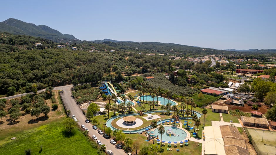 Aerial photograph of a vibrant summer resort in Corfu, Greece, featuring pools and lush greenery.