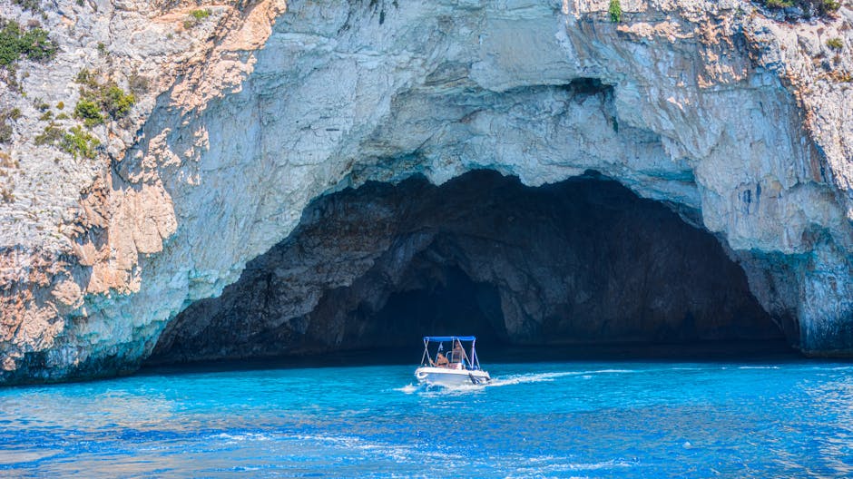 A boat approaches a stunning blue-hued cave entrance against rocky cliffs.