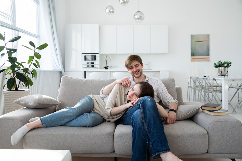 A happy couple enjoying a relaxing moment on a sofa in a bright, modern living room.