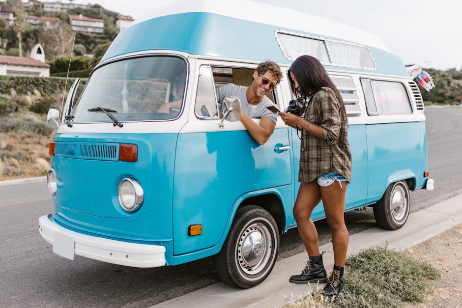A couple enjoying a road trip with a vintage Volkswagen camper van on a sunny day.