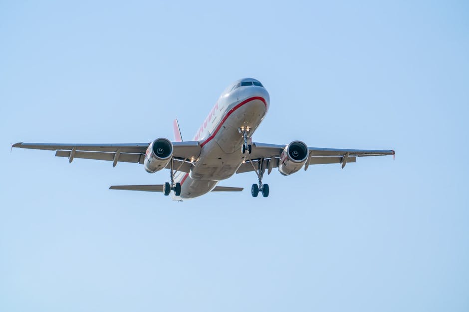 An Airbus A320 in flight descending over Manises, Valencia. Clear blue sky.