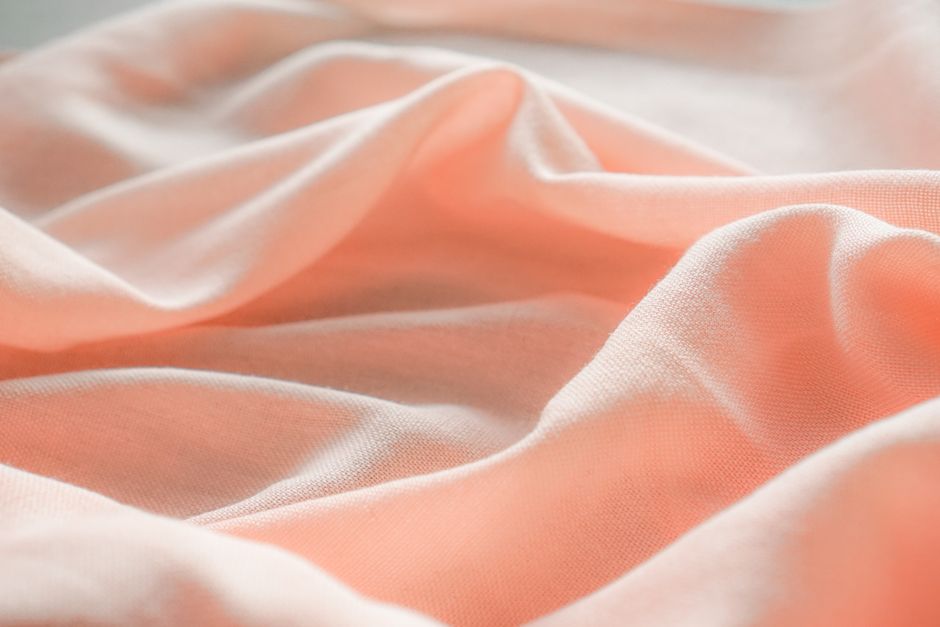Close-up of pastel pink fabric with gentle folds, ideal for textile and design projects.