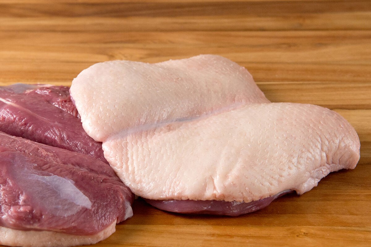 Duck breasts with skin side visible on a wood board