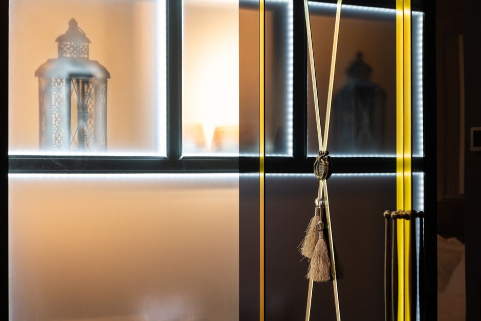 Lantern with ornament on shelf with shiny light against hanging tassels in house room