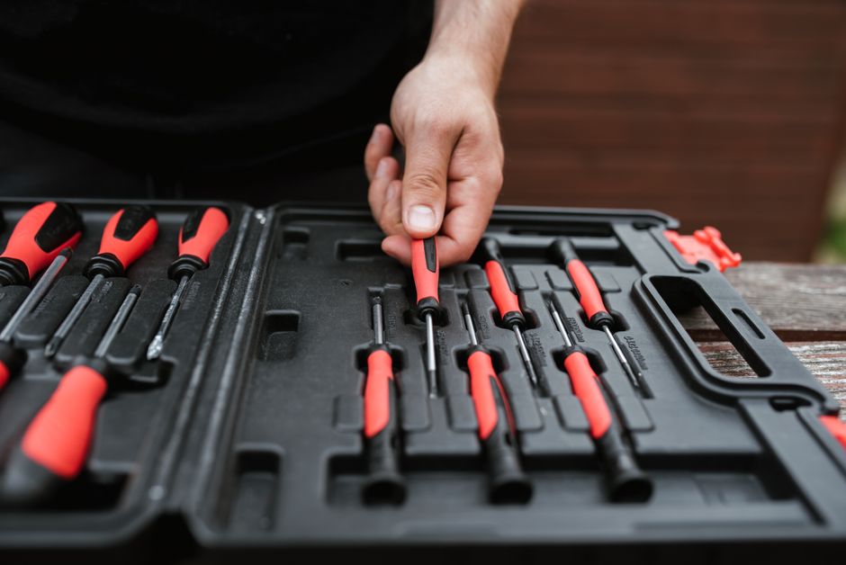From above of crop anonymous skillful male in casual clothes choosing screwdriver from too