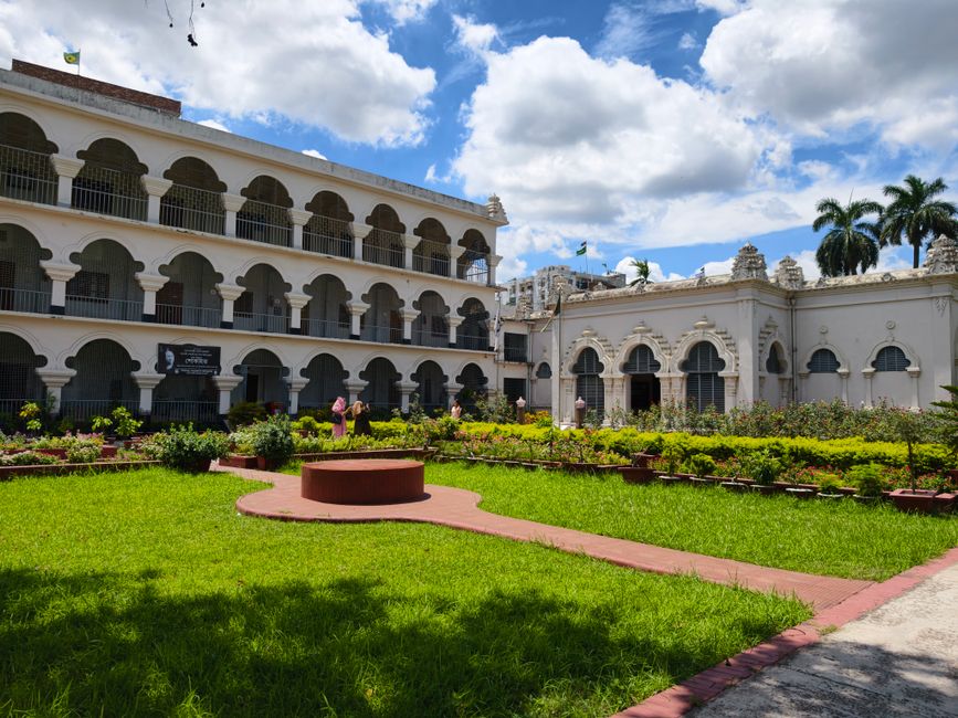 Beautiful colonial-style building with a vibrant garden under a bright blue sky.