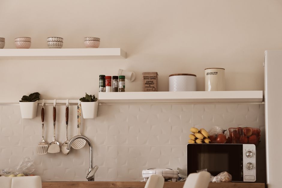 Stylish modern kitchen with minimalist shelves and appliances in warm tones.