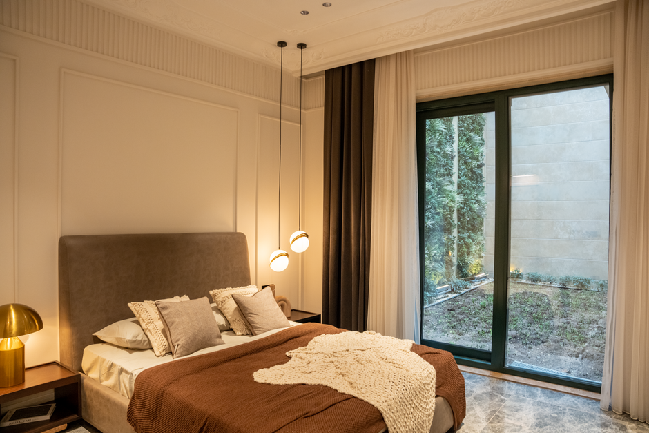 A luxurious modern bedroom with plush decor and large sliding doors overlooking a garden.