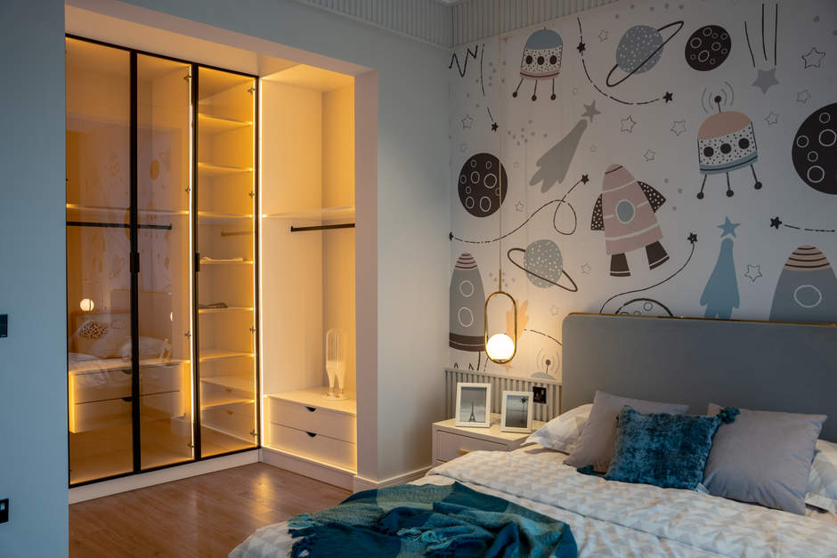 A cozy and stylish kid's bedroom featuring space-themed wallpaper and modern furnishings.