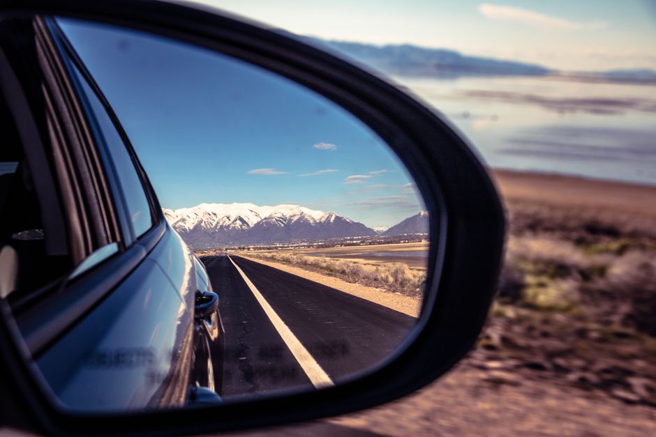 A dynamic view of a road and mountains reflected in a car's side mirror near Salt Lake City.