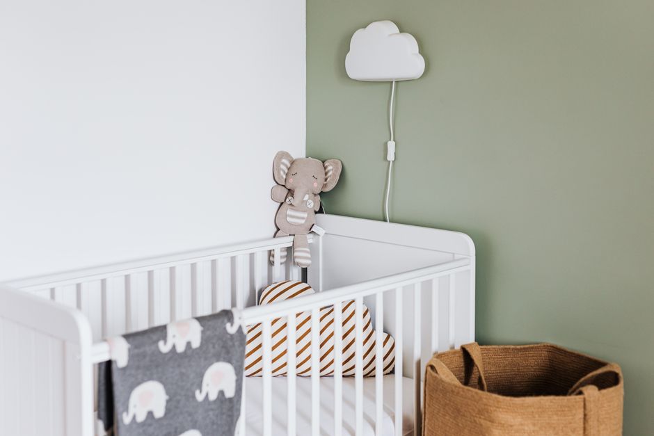 Modern baby room featuring a white crib, soft decor, and pastel accents.