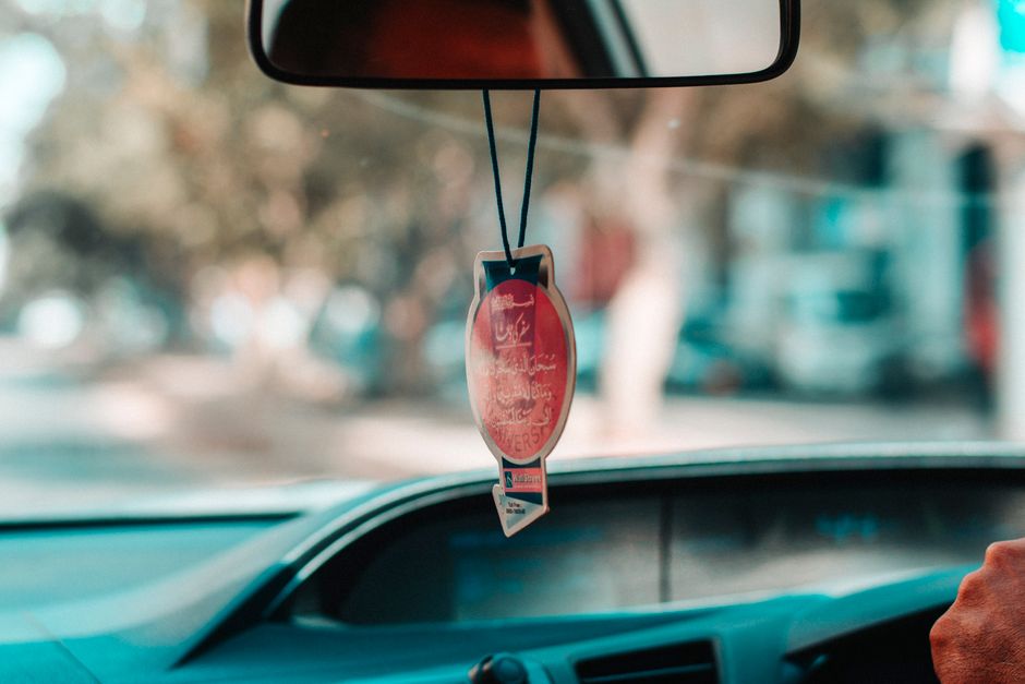 Interior car view showcasing a hanging ornament and blurred road scene for a travel vibe.