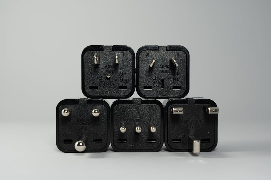 A collection of various black international power plug adapters for global electronics use.