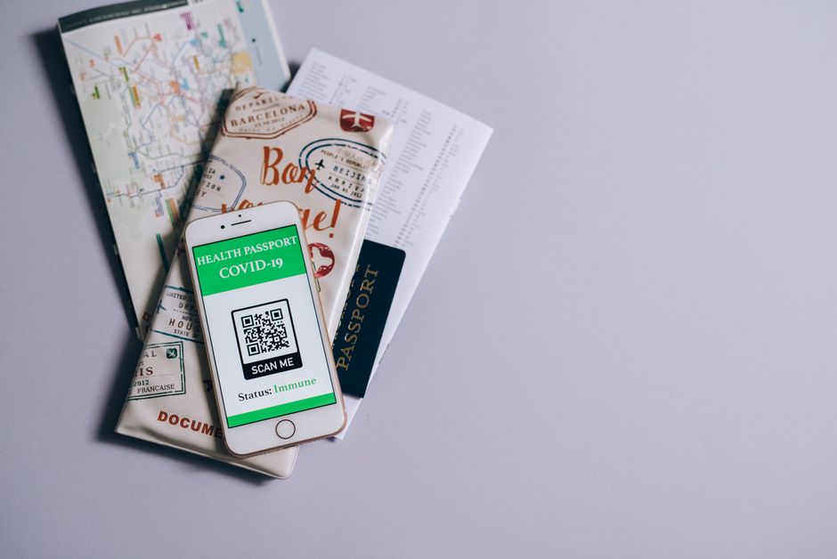 A health passport for COVID-19 displayed on a smartphone alongside travel documents.