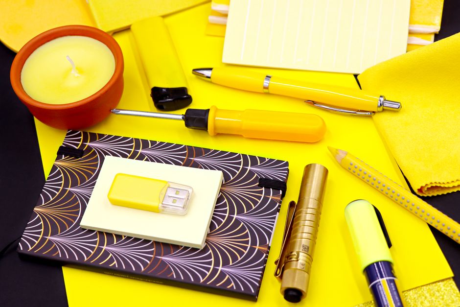 Eye-catching flat lay of yellow office supplies, including USB stick, pen, and candle, perfect for bright workspaces.
