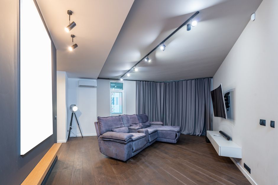 A stylish living room featuring a gray sofa, mounted TV, and elegant lighting.