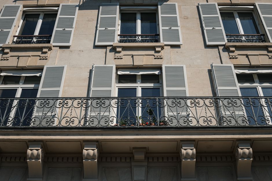 Elegant Parisian apartment facade with ornamental iron balcony and shutters in the city of Paris.