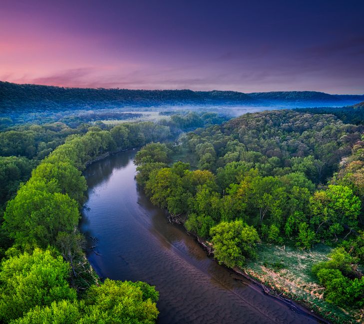 Stunning aerial panorama of a lush riverbend surrounded by dense forest and vibrant twilight skies in Kellogg, Minnesota.